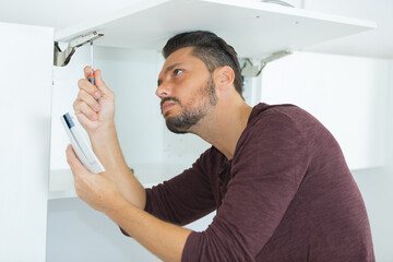 man following instructions to assemble kitchen cupboard