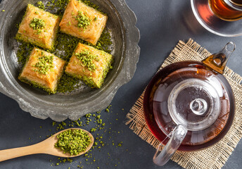 Traditional turkish dessert pistachio antep baklava with turkish black tea on rustic table,  ramadan or holiday desserts concept
