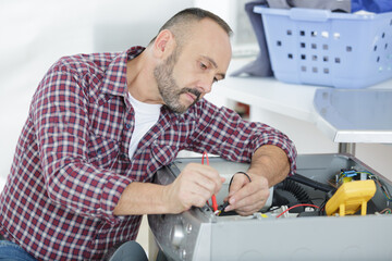 male technician inspecting and fixing a washer and dryer