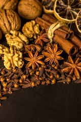 Traditional Christmas spices - Star anise with cinnamon and cloves and wallnuts on black rustic wooden background. Medicinal spices.