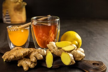 Ginger tea in a cup on black wooden background. Treatment of flu and colds. Healthy tea.