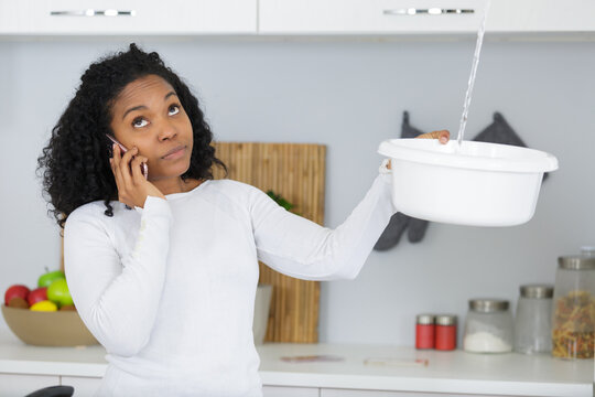 stressed woman calling plumber to fix water leaking from ceiling