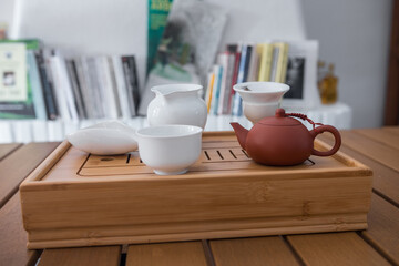 Fototapeta na wymiar Gong Fu Cha tea set. Beautiful bamboo tray with white porcelain teaware (tea leaves, chahe, gaiwan, gong dao bei, cups...). Traditional way of drinking tea in China with a clay teapot.