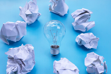Light bulb with white crumpled paper on blue background. Ideas and creative thinking concept. Top...