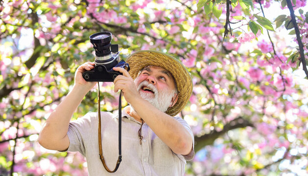 Senior man hold professional camera. Photography courses. Happy grandfather. Travel and tourism. Spring holidays. Travel photo. Retirement travel. Capturing beauty. Photographer in blooming garden