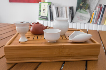 Fototapeta na wymiar Gong Fu Cha tea set. Beautiful bambou tray with white porcelaine teaware (tea leaves, chahe, gaiwan, gong dao bei, clay teapot, cups...) Traditional brewing method. Yunnan, China.
