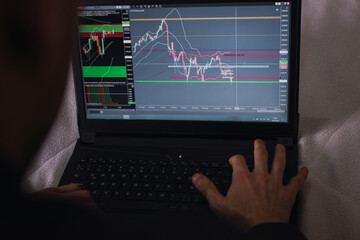 Forex market. Young trader draws graphs on computer screen and analyzes data while working.