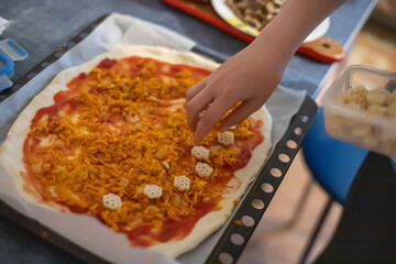 Hand Adding ingredients on homemade pizza. Simple food made from cheap foods. Preparing food at home.