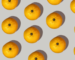 A pattern of big orange mandarins with a pronounced shadow on a beige background. Mandarin set, healthy food.