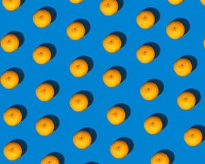 A pattern of little bright orange mandarins with a pronounced shadow on a bright blue background.  Mandarin set, healthy food.