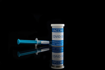 Close up of a vial and a syringe with coronavirus vaccine. Covid-19 vaccine in a syringe on a black background.