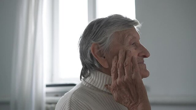 Old Senior Woman Grandmother Taking Care Of Skin Near Eyes And Applying Anti-wrinkle Eye Patch, Putting Makeup On. Elderly Grandma Doing Make-up Procedures At Home. Cosmetics For Retired Pensioners