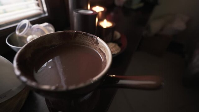 Accessories for spa treatments and aromatherapy with melted chocolate and chocolate candles. Action. Close up of a bowl with hot cosmetic chocolate and burning candles on the background.