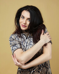 the attractive brunette wrapped her arms around herself. photo session in the Studio on a yellow background