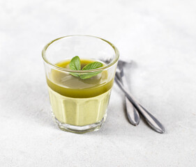 Jelly creamy green matcha tea in a glass on a light gray background