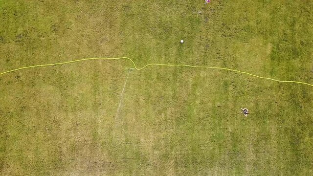 Top down aerial view of football field surface covered with green grass and sprinklers spraying water.
