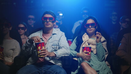 Cheerful friends laughing in cinema. Joyful couple watching movie in hall.