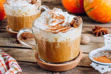 Pumpkin spiced latte or coffee in a glass on a vintage table. Autumn or winter hot drink.