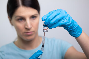 Doctor scientis in protective gloves and mask holding glass vial with injection liquid. Vaccination against influenza and coronavirus.