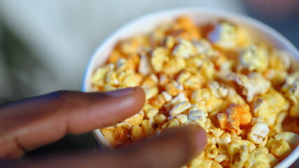 Closeup man hands taking snack from fool box. Afro american guy eating popcorn.