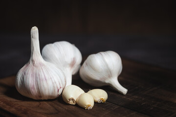 Garlic cloves and bulb on cutting board in vintage wooden bowl