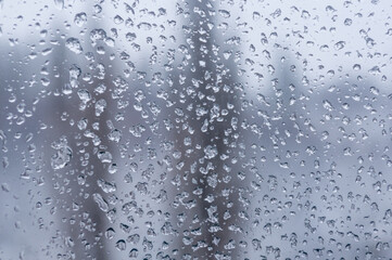 Melting snow on the glass, drops of water condensation on the window, and transparent glass of the window in cold winter, winter landscape outside the window, close-up.