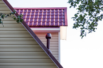 The facade of the new house clad with siding, with windows, against the blue sky.