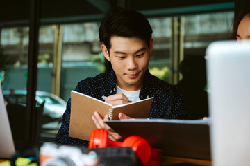 Man taking note in meeting with business people at cafe.