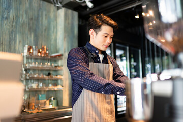Barista man making coffee with machine behind the bar in cafe.