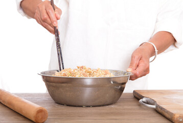 The chef is mixing pork dumplings with green onions