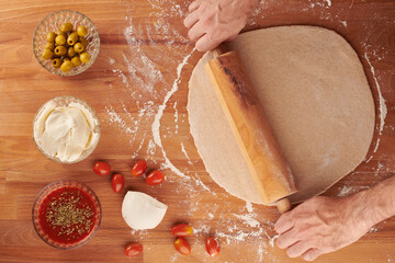 Making italian pizza step by step: dough rolled out with a rolling pin