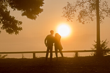 Silhouette young couple enjoying the sunrise in the mountain sea mist.