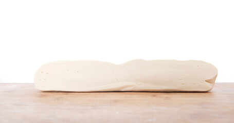 A loaf of white dough on a cutting board in front of white background