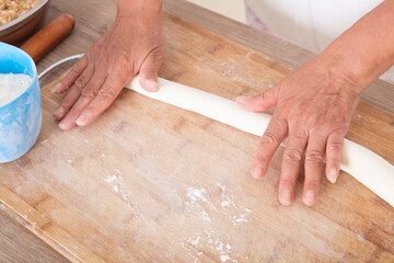 The pastry chef rolls the dough into strips before making dumplings