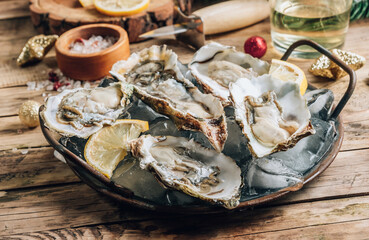 Oysters with lemon on a vintage dish on a rustic wooden background with a festive decor. Christmas dinner.