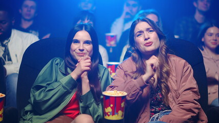 Smiling girls spending time in movie theater. Women looking film in cinema.