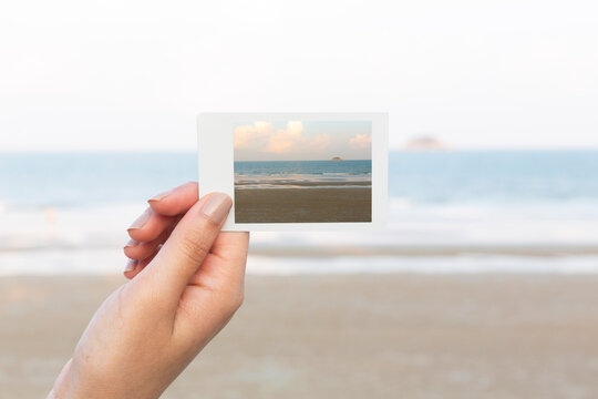 Hand holding picture of sea on sea background