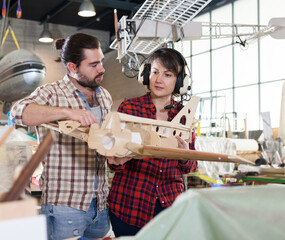 Positive couple enjoying their hobbies - modeling light airplanes in aircraft hangar