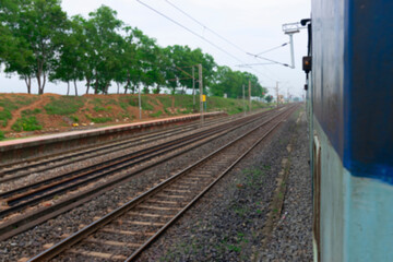 Obraz premium Blurred image of Indian rail lines with green trees in the side.