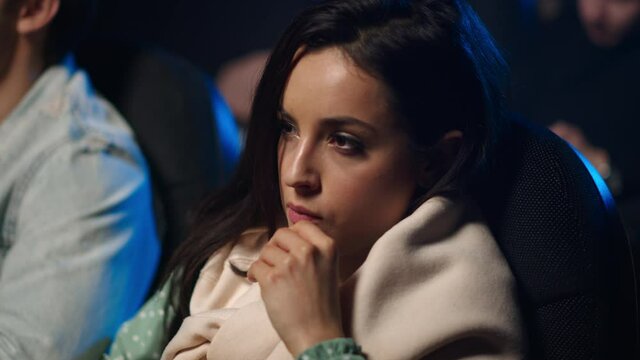 Shocked woman eating popcorn in cinema. Pretty girl looking movie screen indoor.