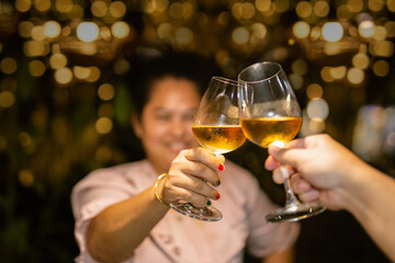 Couple clinking glass of white wine for celebration.