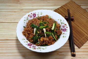 Fried and stirred spicy rice noodle mixed with local sauce and cutting spring onion serving on the plate. Famous traditional noodle menu in Asia restaurant. 