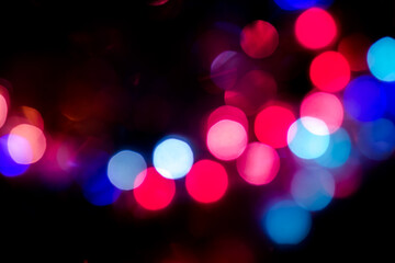 Christmas Night colorful city light black overlay background. Defocused, violet and pink holographic bokeh. Holiday garland decor. Abstract blurred bokeh effect. New year holo flare wallpaper