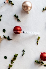 Still life vaccine syringe and Christmas decorations ornaments top view on white background flatlay