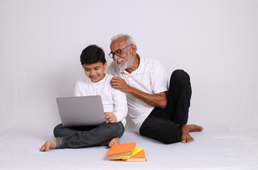 Fototapeta premium Indian grandfather teaching grandson home schooling or tuition.