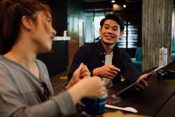 Asian business man talking to woman in cafe.