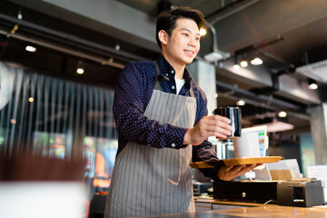 Asian waiter man serving hot coffee to customer in cafe.