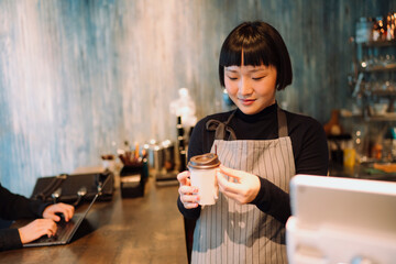 Barista woman making hot coffee in cafe for customer.
