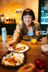 Cheerful asian short hair woman having lunch with friend in kitchen room.