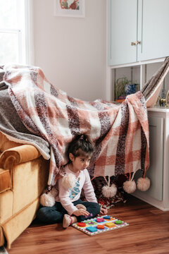 Child Playing In Front Of Blanket Fort At Home